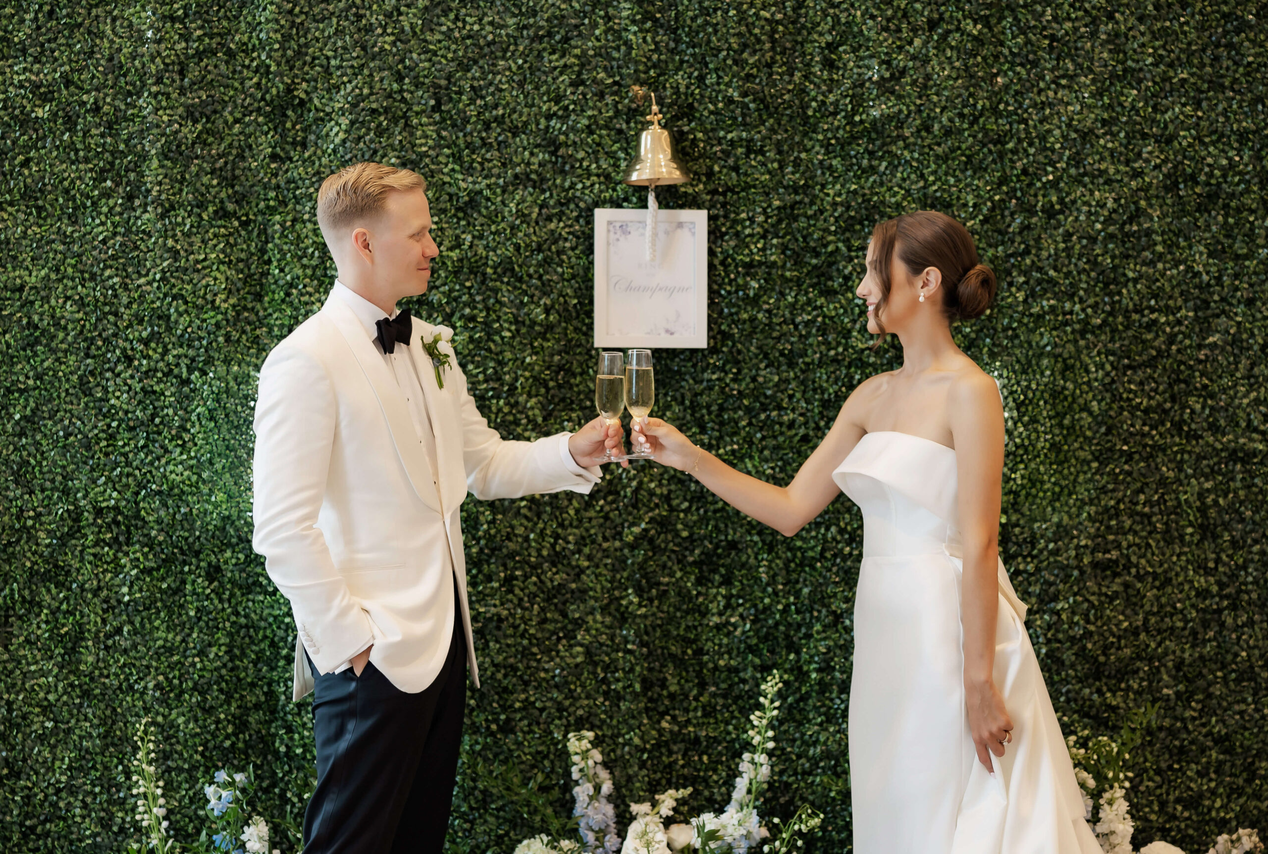 Couple cheers in front of living champagne wall